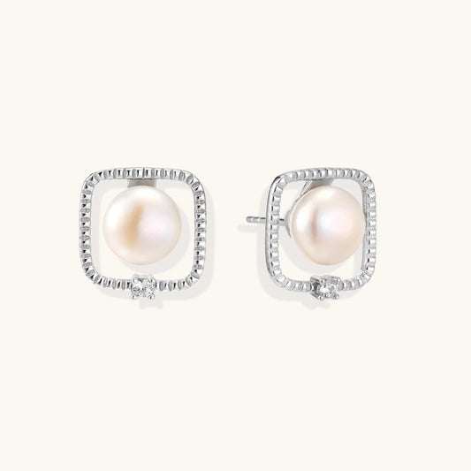 Rhodium-plated silver stud earrings with cushion frame, centered freshwater pearl, and tiny crystal accent