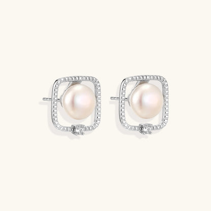 Rhodium-plated silver stud earrings with cushion frame, centered freshwater pearl, and tiny crystal accent