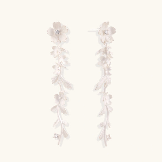 Long sterling silver drop earrings with delicate floral vine design and crystal accents on white background